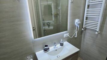 Une salle de bain moderne avec une douche à parois de verre, un lavabo blanc avec un miroir au-dessus et un porte-serviettes fixé au mur.