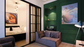 Una habitación de hotel moderna con una cama, un sofá, un escritorio y una pared verde decorativa.