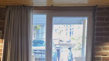 A room with a window, wooden beams, and a brick wall.