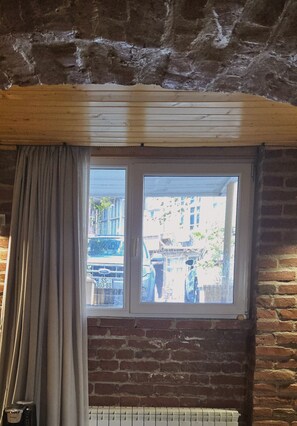 A room with a window, wooden beams, and a brick wall.