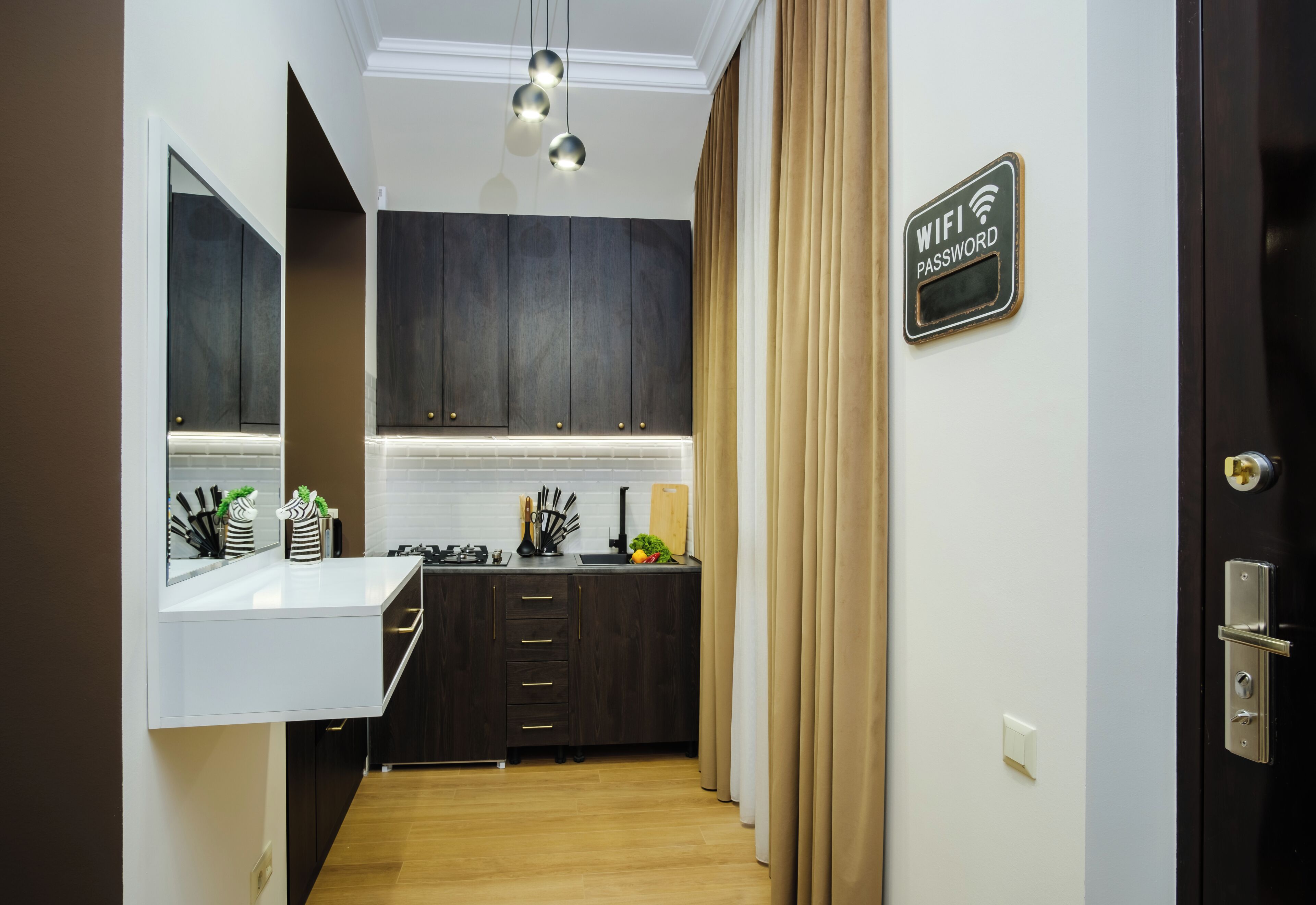 A modern kitchen with dark cabinetry, a white countertop, and a sign indicating WiFi password availability.