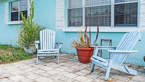 A patio with two Adirondack chairs, a potted plant, and a small table. - Beach Bungalow Near Ormond Beach and the Atlantic (Ormond Beach)