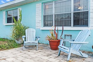 Eine Terrasse mit zwei Adirondack-Stühlen, einem Blumentopf und einem kleinen Tisch.
