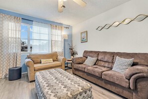 A living room with a sofa, a smaller couch, a coffee table, and a lamp. - Beach Bungalow Near Ormond Beach and the Atlantic (Ormond Beach)