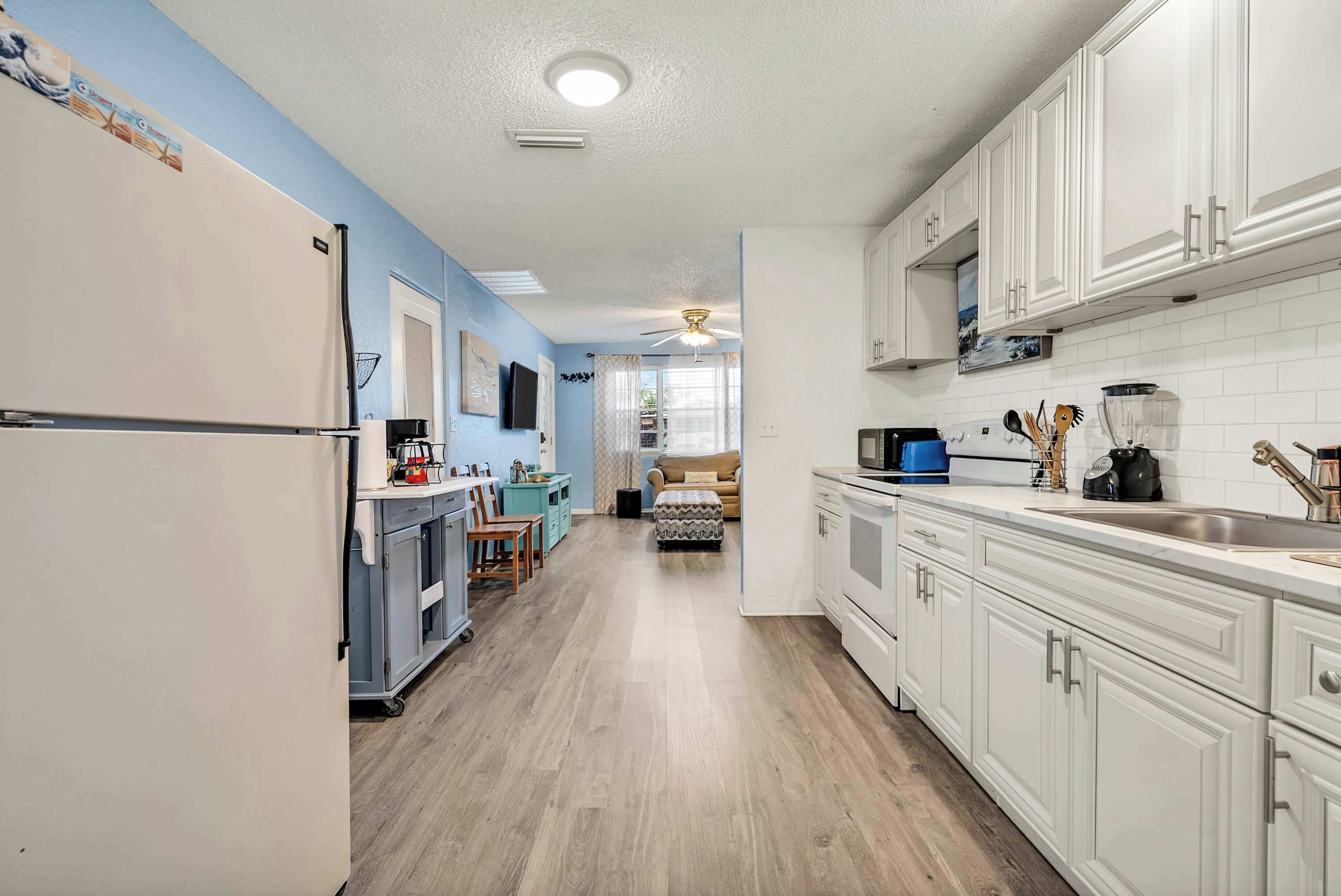 A kitchen with white cabinets, a refrigerator, a microwave, and a sink.