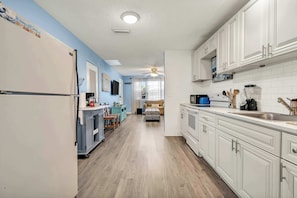 A kitchen with white cabinets, a refrigerator, a microwave, and a sink. - Beach Bungalow Near Ormond Beach and the Atlantic (Ormond Beach)
