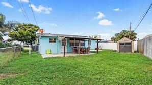 A residential property with a fenced yard, a small porch, and a garage. - Beach Bungalow Near Ormond Beach and the Atlantic (Ormond Beach)