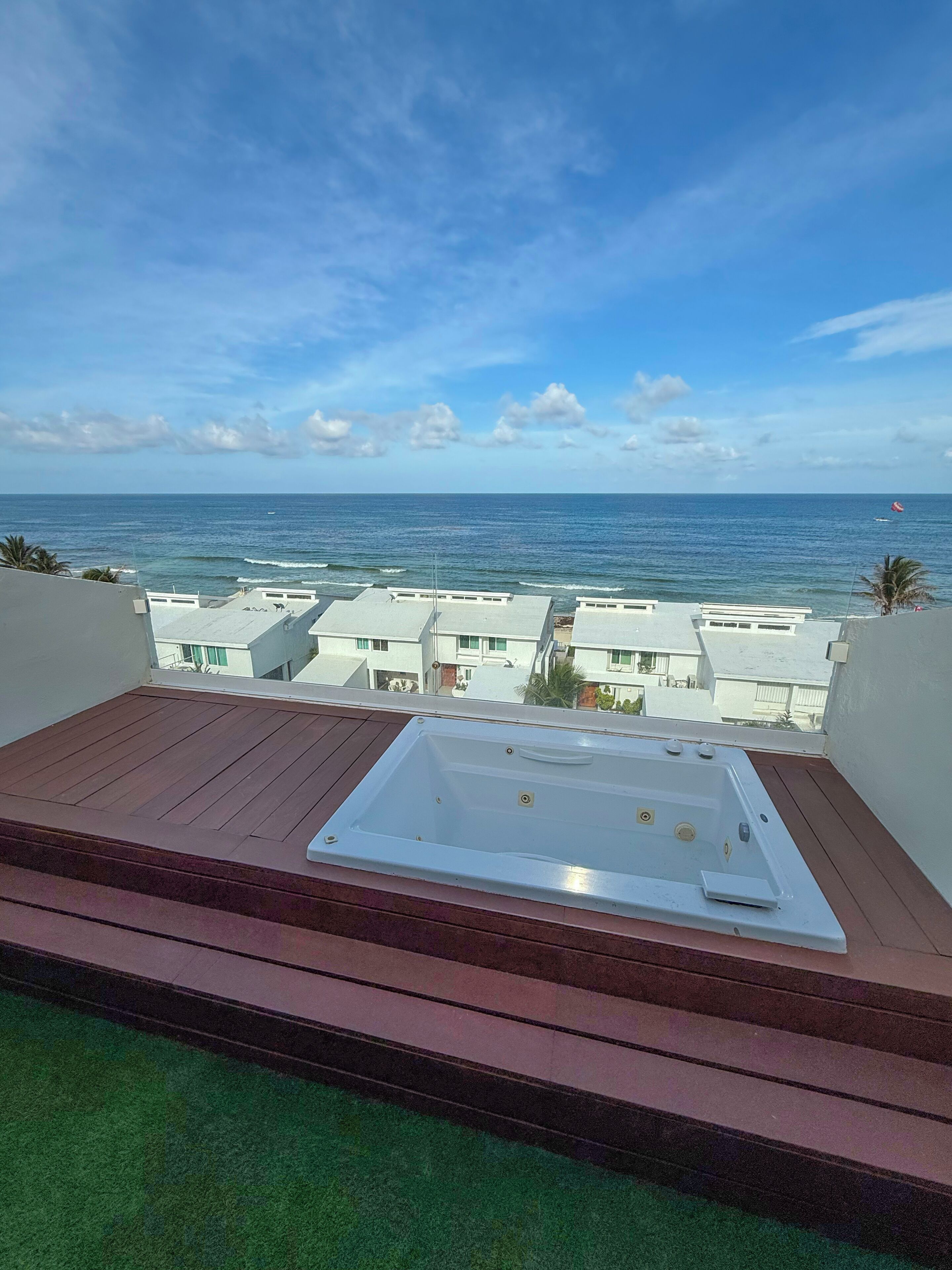 Eine Dachterrasse mit Whirlpool, mit Blick auf ein Wohngebiet und das Meer.
