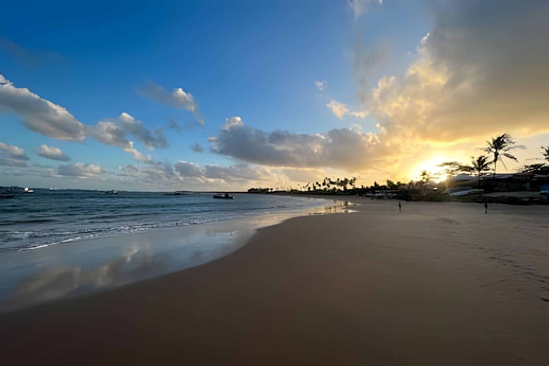 A beach with a calm sea, a clear sky, and a sunset.