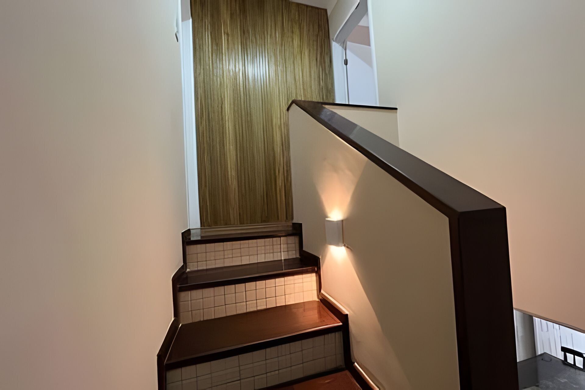A staircase with wooden steps and a handrail, leading to a room with a wooden door.