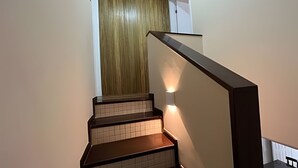 Una escalera de madera con barandilla que conduce a una habitación con puerta de madera.