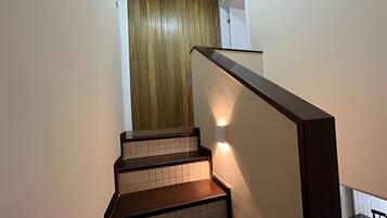 A staircase with wooden steps and a handrail, leading to a room with a wooden door.