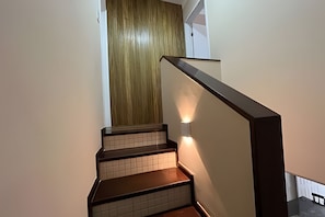Una escalera de madera con barandilla que conduce a una habitación con puerta de madera.