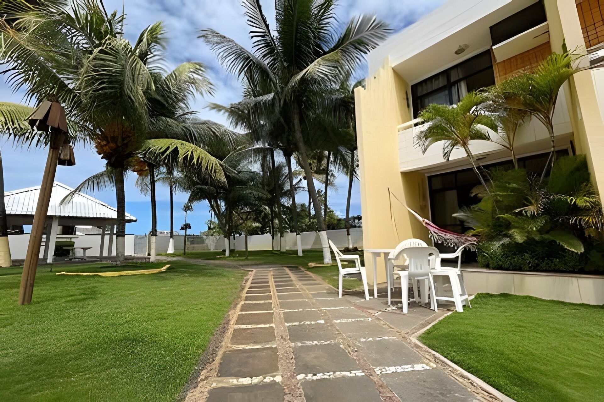Un patio con sendero adoquinado, palmeras y mobiliario exterior.