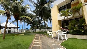 Un patio con sendero adoquinado, palmeras y mobiliario exterior.