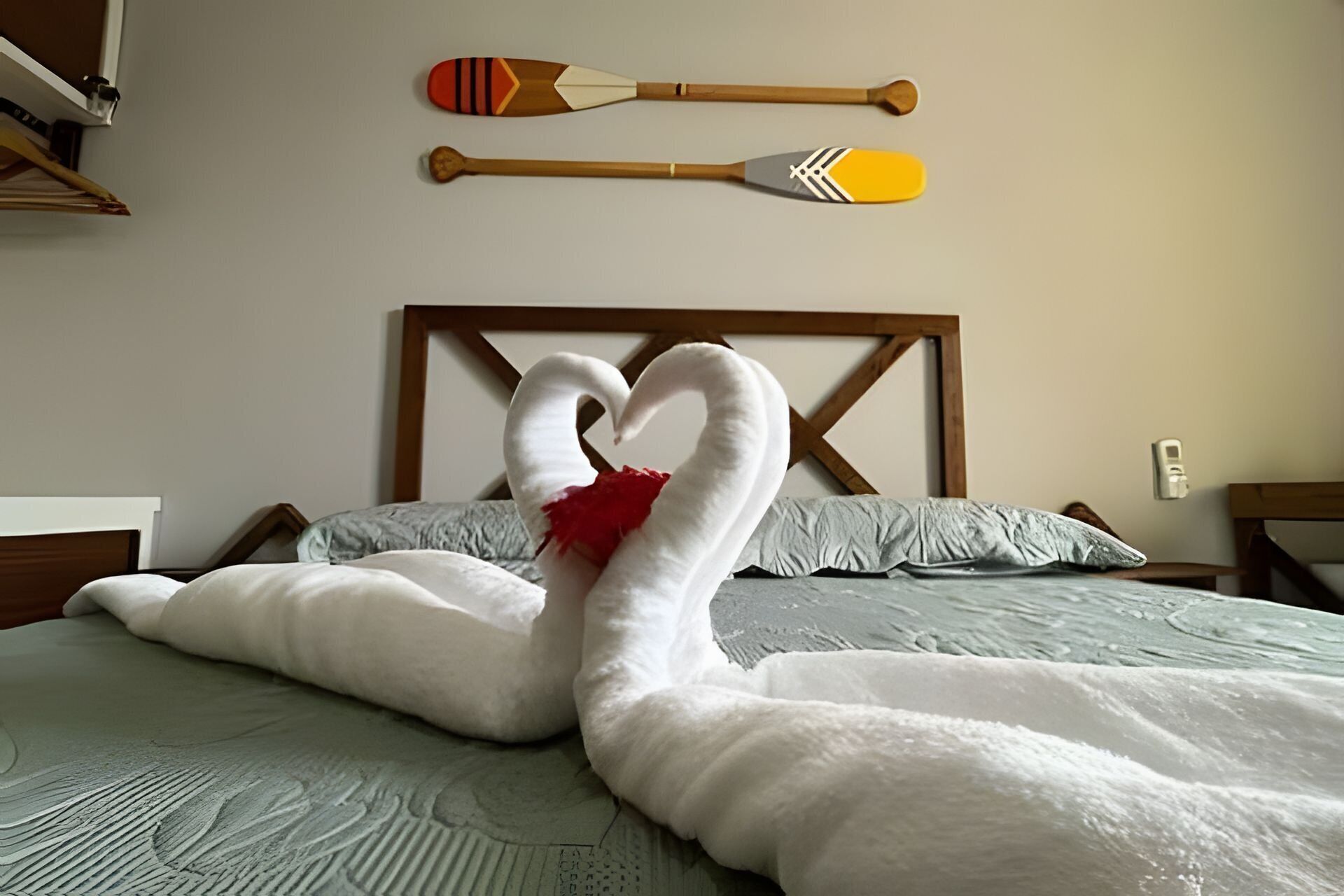 Una cama con un arreglo de almohadas en forma de cisne y dos remos colgados en la pared.