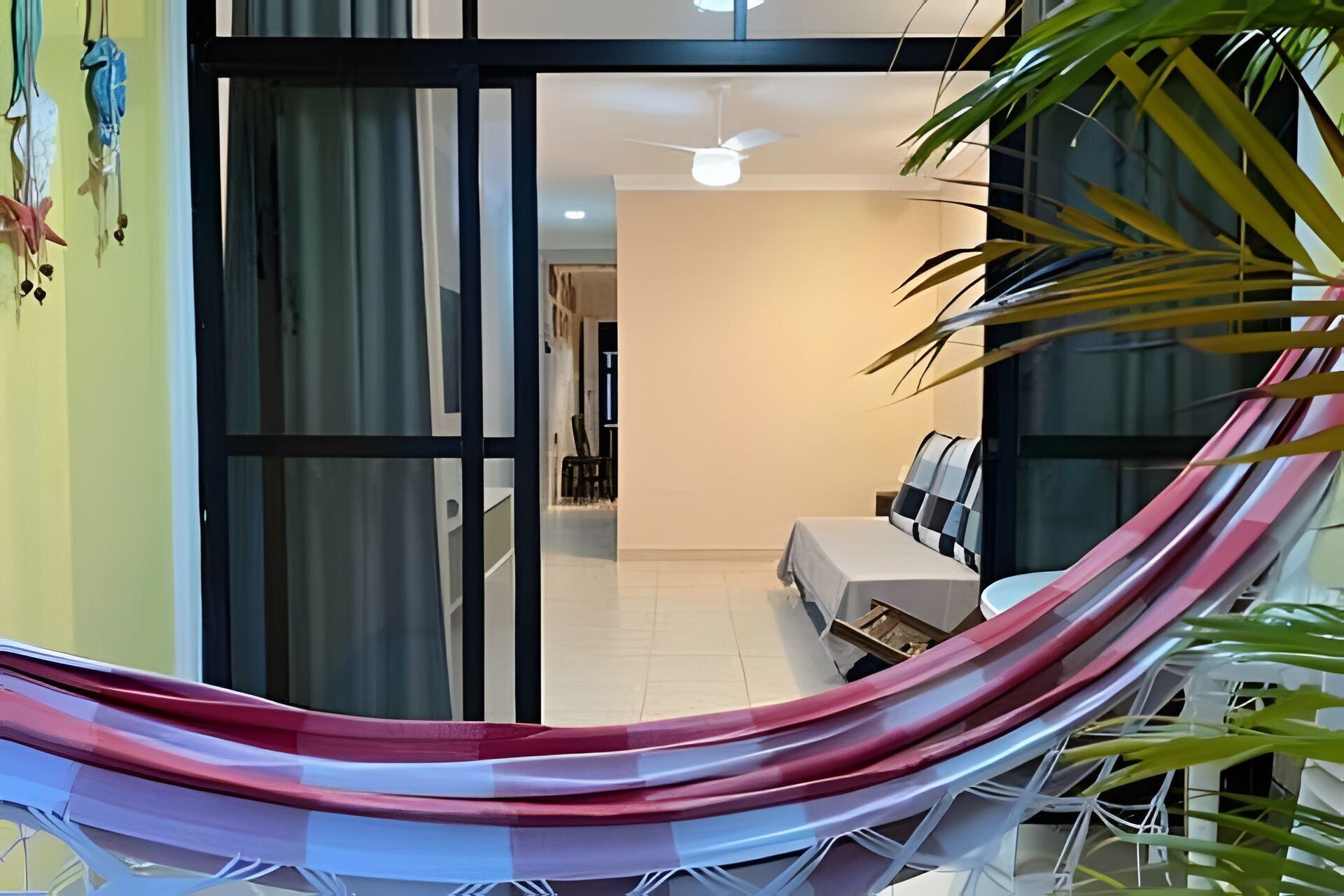 Une chambre avec un lit, un ventilateur de plafond et une vue sur l’extérieur, visible à travers une porte vitrée.