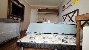 Un dormitorio pequeño con cama, ventana y cabecera de madera.