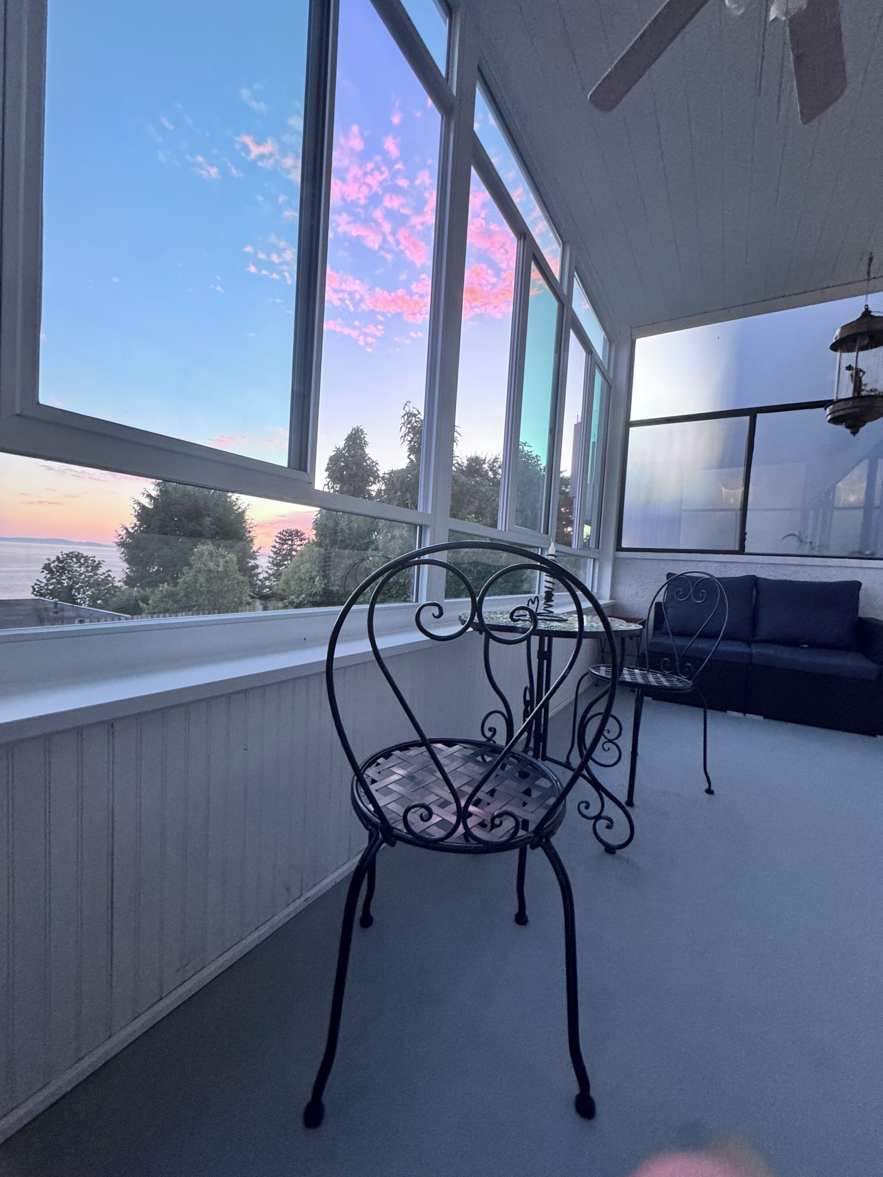 A balcony with a metal chair, a small table, and a sofa.