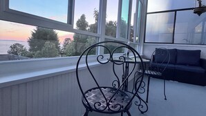 Un balcón con una silla de metal, una mesita pequeña y un sofá.