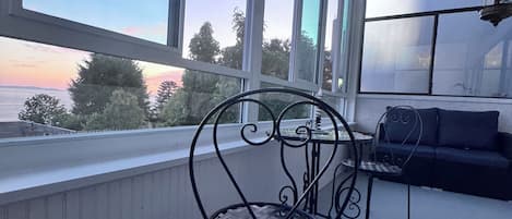 A balcony with a metal chair, a small table, and a sofa.