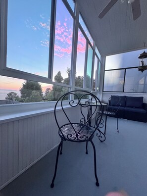 A balcony with a metal chair, a small table, and a sofa.