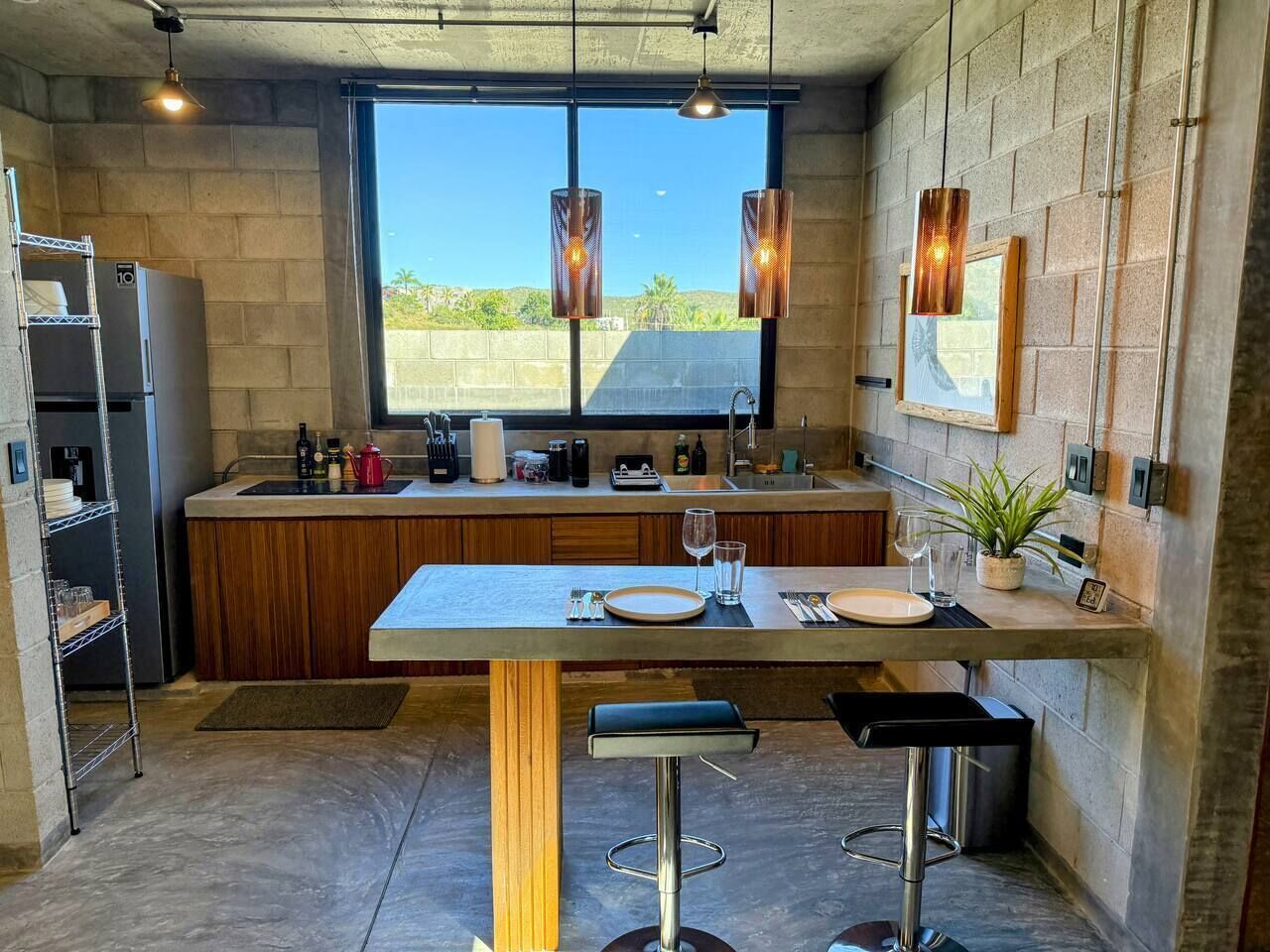 Una cocina moderna con un ventanal grande, una barra y una mesa de comedor para dos.