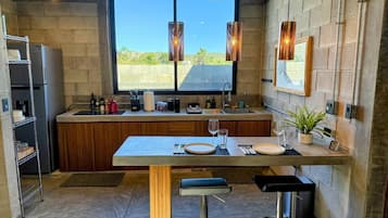 Una cocina moderna con un ventanal grande, una barra y una mesa de comedor para dos.