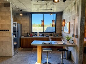 Una cocina moderna con un ventanal grande, una mesa de comedor y taburetes de bar.