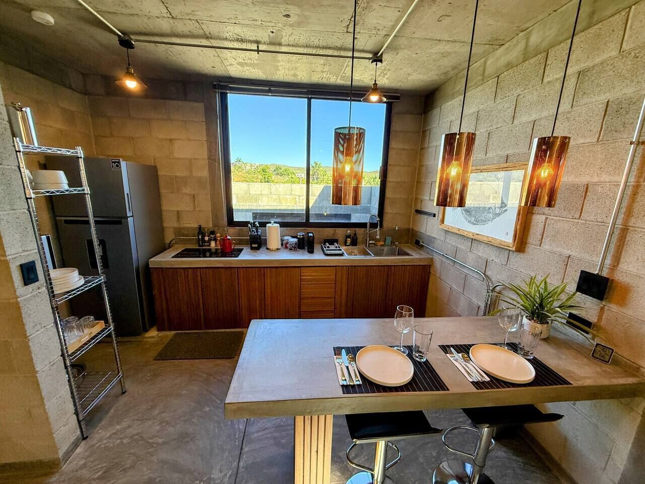 Cocina moderna con comedor, refrigerador, lavamanos y ventana con vistas.