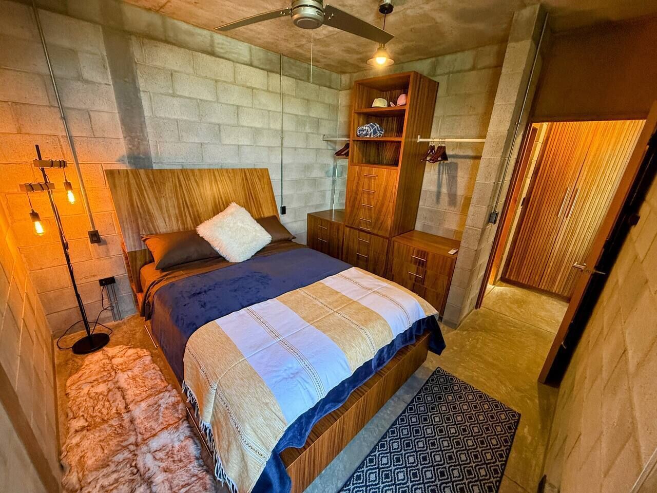 Un dormitorio con cama, armario de madera y ventilador de techo.