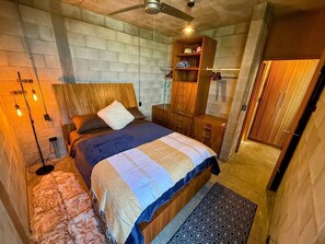 A bedroom with a bed, wooden wardrobe, and a ceiling fan.