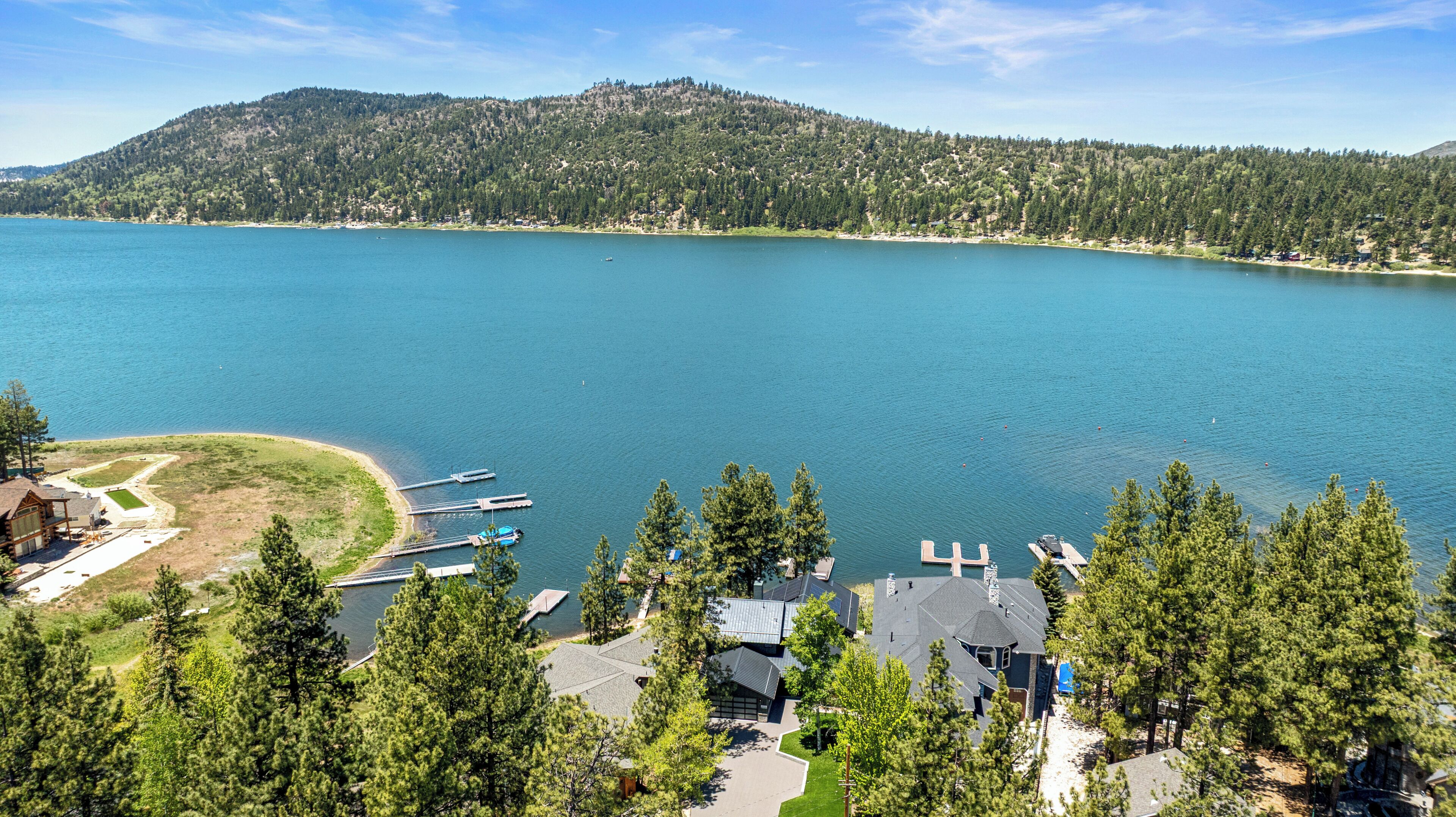 A lake with a dock and a cabin area surrounded by trees.