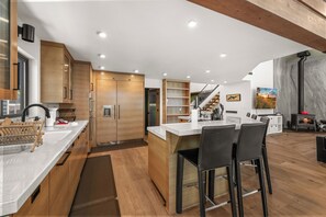 Una cocina moderna con armarios de madera, una isla central con taburetes y vistas al área de estar.