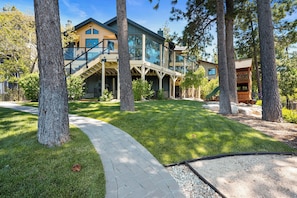 A modern house with a glass facade, a covered outdoor area, and a stone pathway. - Emerald Lakefront Chalet (Big Bear Lake)