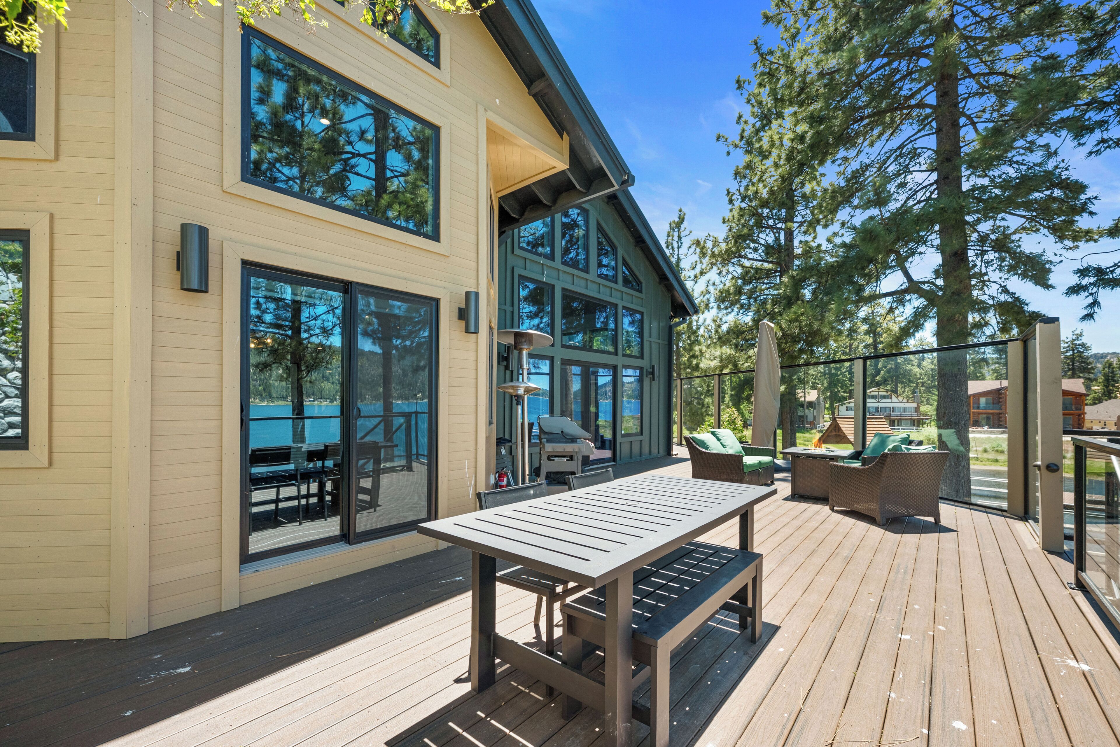 A modern house with a deck, large windows, and outdoor furniture.