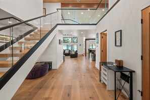 Un interior moderno con una escalera, piso de madera y un comedor.