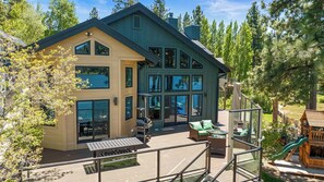 Una casa de dos pisos con ventanas amplias, mobiliario exterior y una terraza.