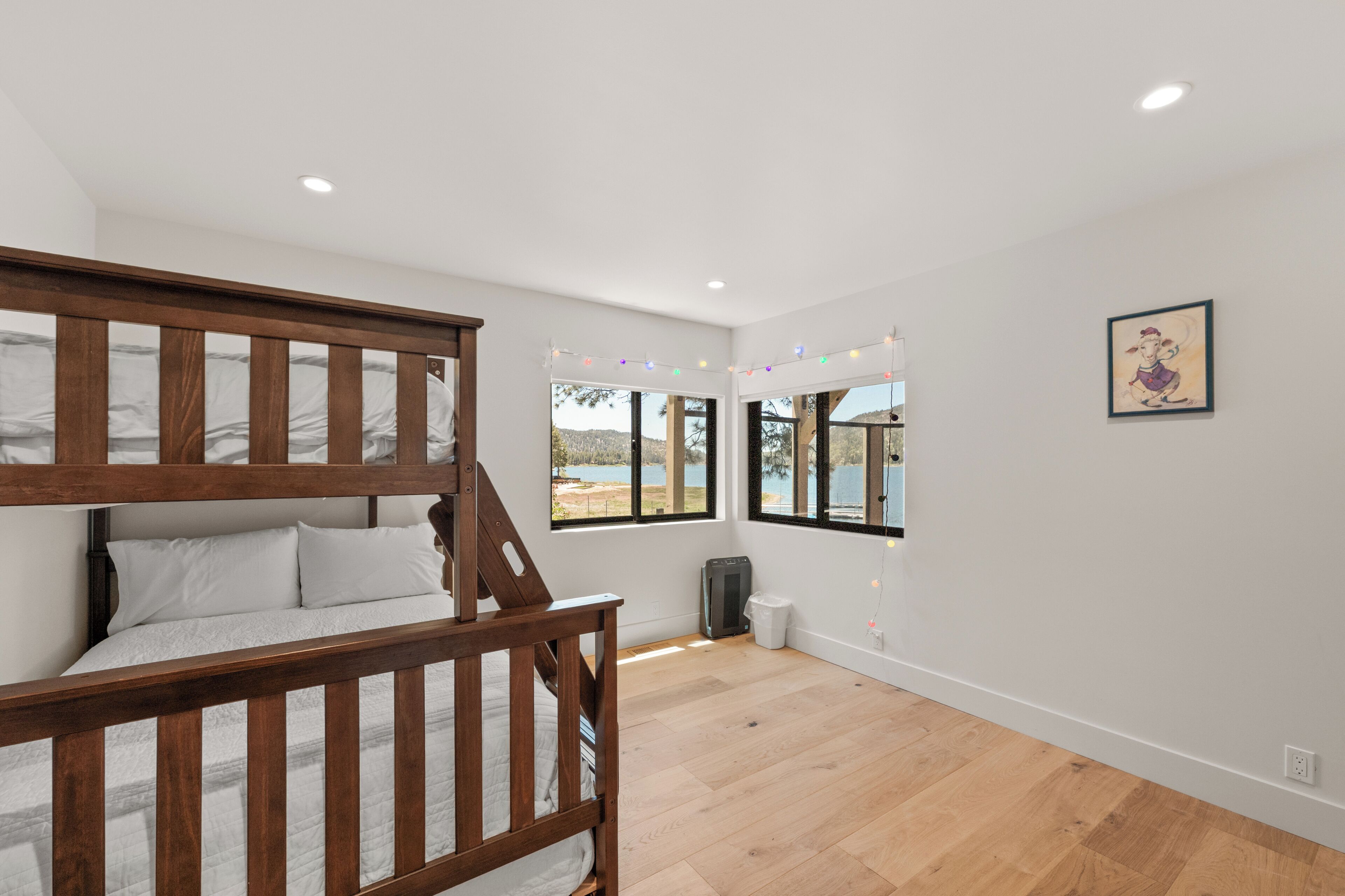 A room with a bunk bed, large windows, and a view of a lake.