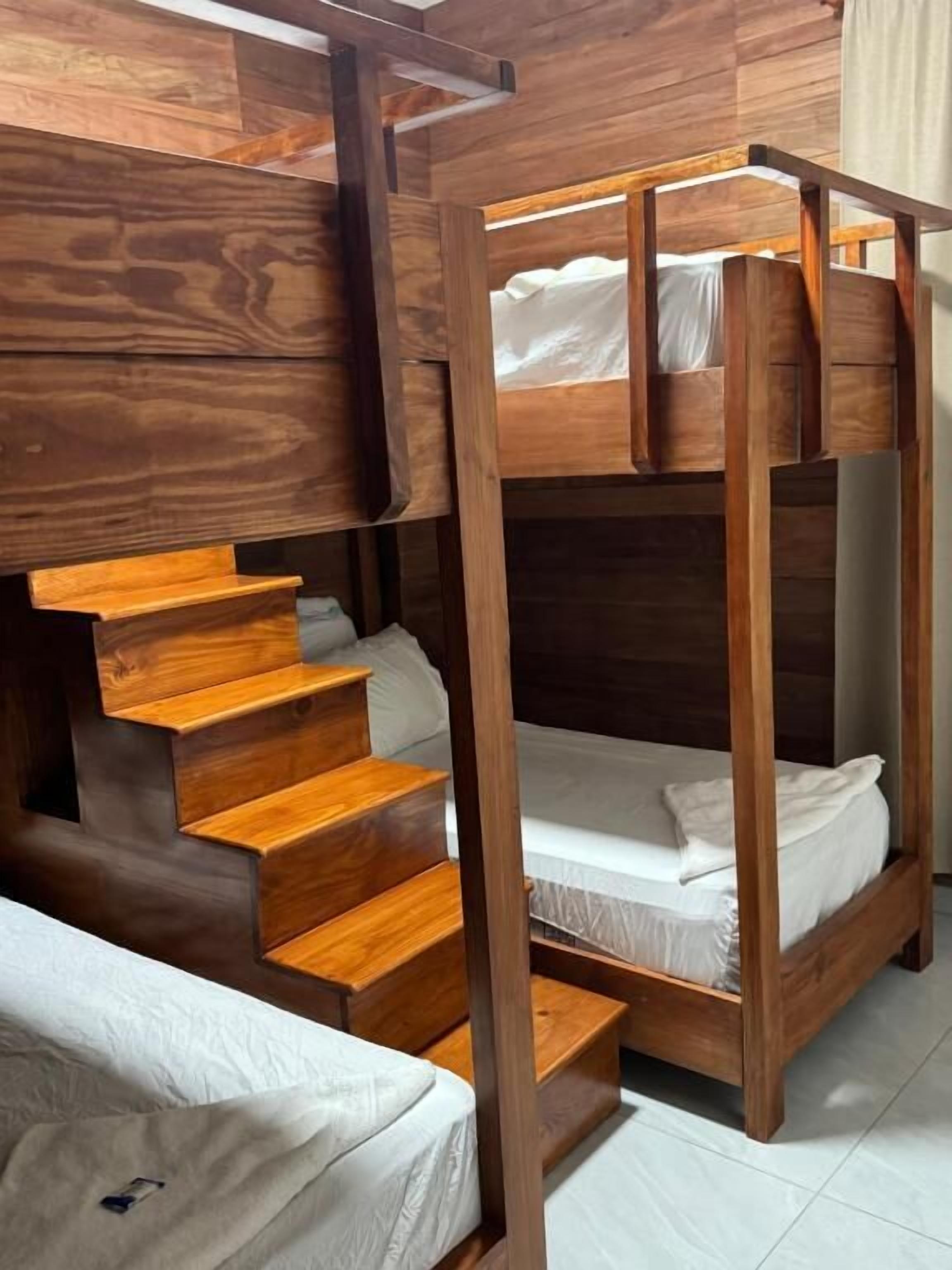 Una cama litera con escalera de madera que lleva a una zona elevada.