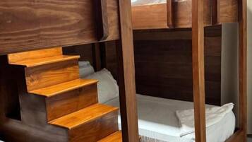 Una cama litera con escalera de madera que lleva a una zona elevada.