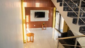 A modern interior with a staircase, a flat-screen TV mounted on a wooden wall, and a seating area with a small table.