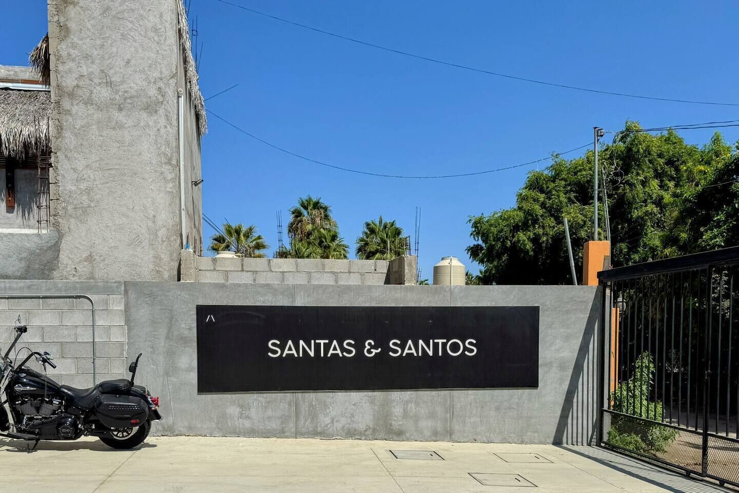 Señalización de 'SANTAS & SANTOS' con una motocicleta estacionada adelante.