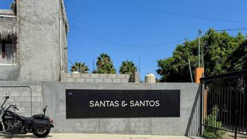 Señalización de 'SANTAS & SANTOS' con una motocicleta estacionada adelante.