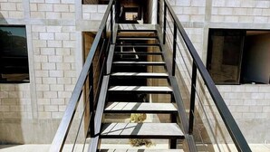 A staircase leading to an entrance of a building with a brick facade and a metal handrail.