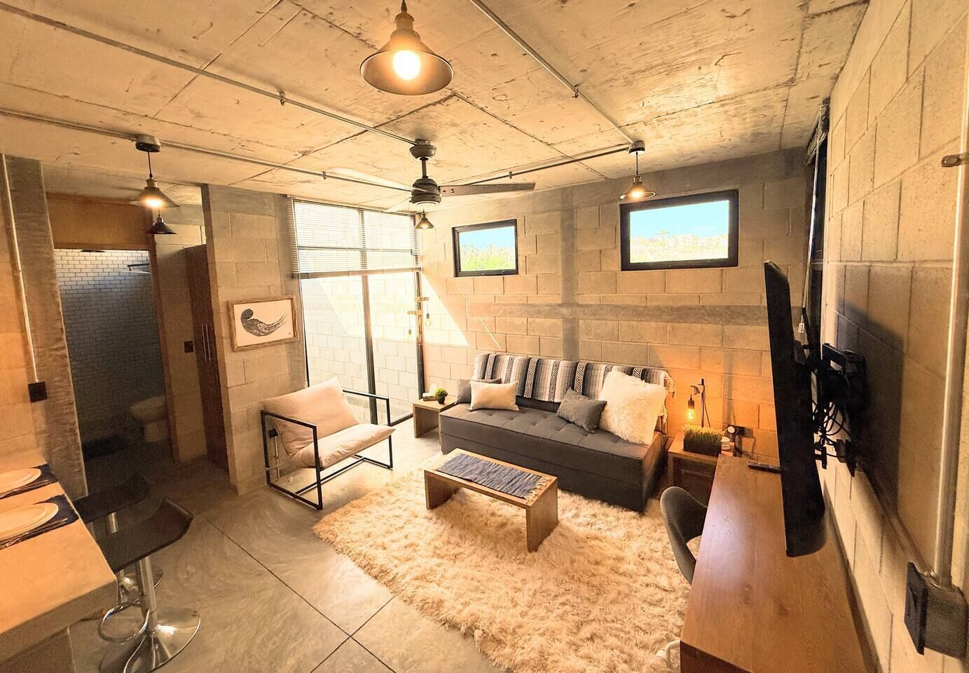 Una sala de estar moderna con un sofá, sillones, una mesa de centro y un televisor montado en la pared.