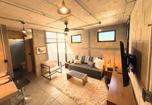Una sala de estar moderna con un sofá, sillones, una mesa de centro y un televisor montado en la pared.