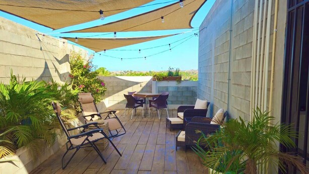 An outdoor patio with wooden flooring, outdoor furniture, and potted plants.