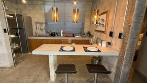 A modern kitchen with a central island, bar stools, stainless steel appliances, and pendant lighting.