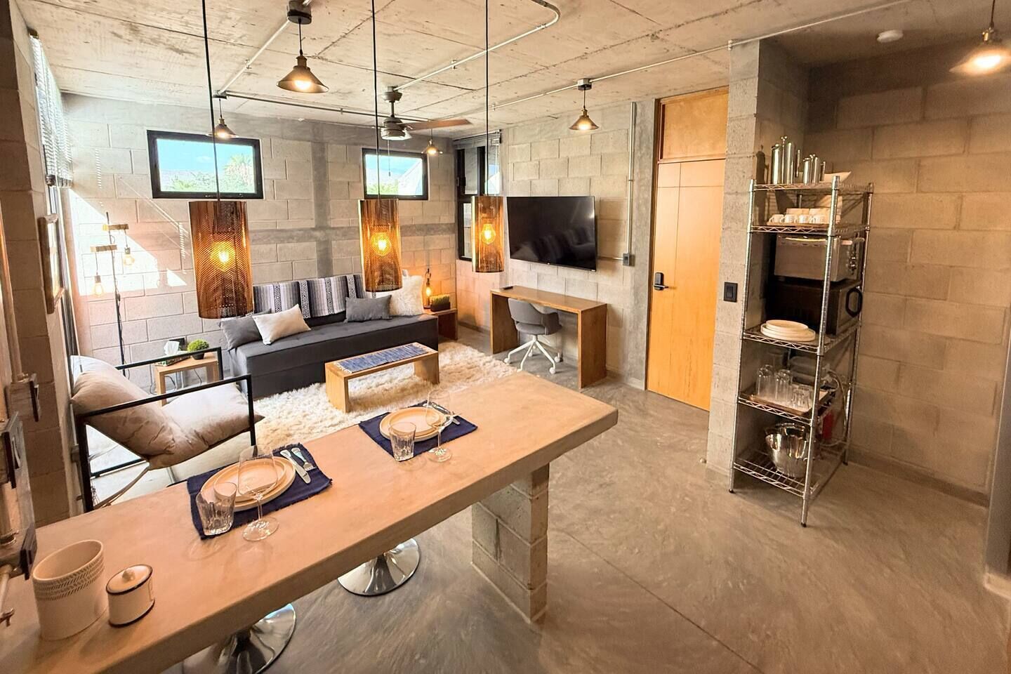 Una cocina moderna con comedor, un sofá y un televisor montado en la pared.